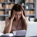 Women on computer looking at paperwork.