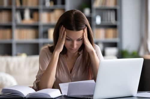 Women on computer looking at paperwork.