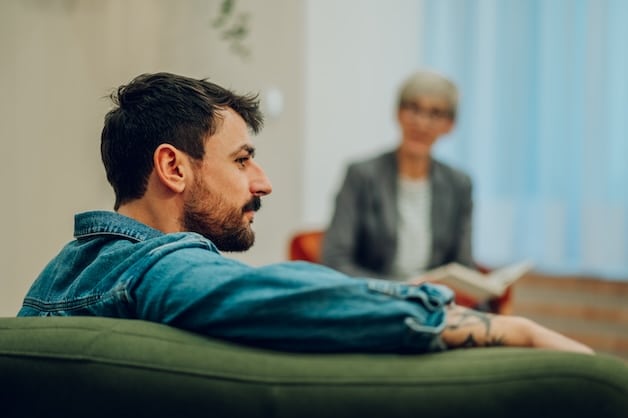 man sitting on couch in therapy with psychologist