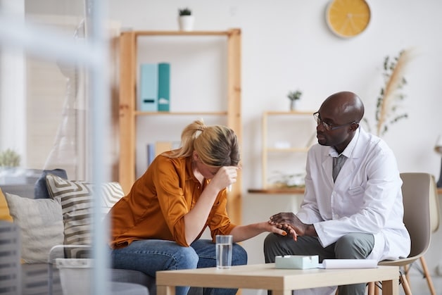 mental health doctor holding hand of patient while giving psychological support to her during therapy