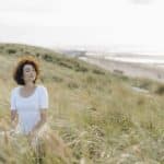 woman doing yoga therapy at beach in the dunes during yoga mental health retreat with amfm