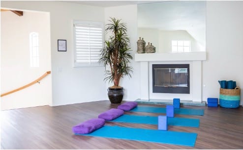 Yoga mats and bolsters set out in a bright therapy room where clients practice yoga to ease anxiety and depression alongside therapy. 