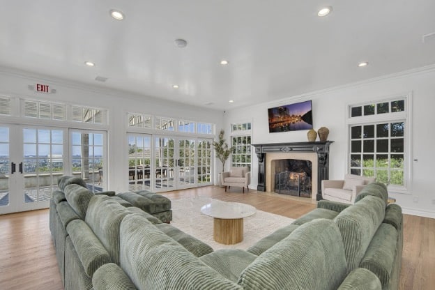 Spacious, bright AMFM living room with green sectional sofas, fireplace, and large windows.