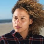 woman sitting outside near a beach with wind blowing her hair, thinking about taking an am i bipolar quiz