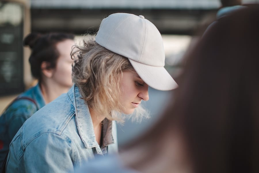 woman in white hat looking down, experiencing anxiety and anger