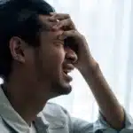 man with hand on head, agonizing over high-functioning schizophrenia