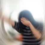 Woman with head in hands and mind spinning, wondering, "what are common symptoms of anxiety disorder?"