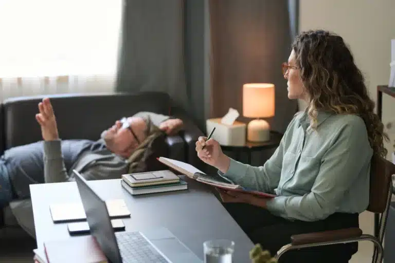 Woman sitting at desk wondering, "Why would I want to relive traumatic memories in therapy?"