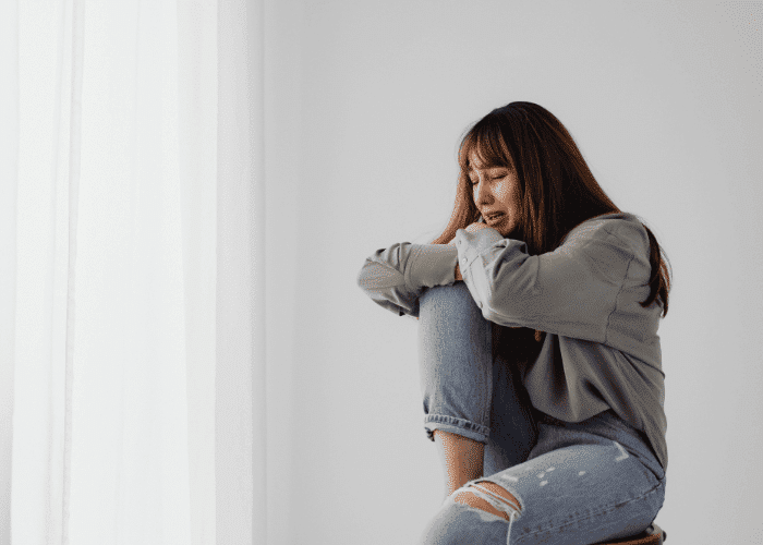 Woman sitting on a chair crying due to anxiety, in need of anxiety treatment