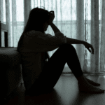 Woman sitting on the floor with her head on her hand, in need of depression treatment