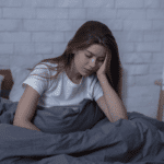 Woman sitting in bed looking depressed, in need of seasonal affective disorder treatment