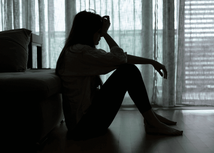Woman sitting on the floor with her head on her hand, in need of depression treatment