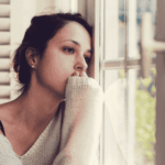woman looking sad looking out the window in need of mood disorder treatment