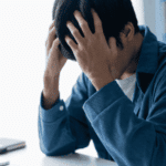 Man sitting at his desk with his head in his hands, in need of ADHD treatment