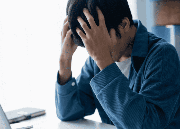 Man sitting at his desk with his head in his hands, in need of ADHD treatment