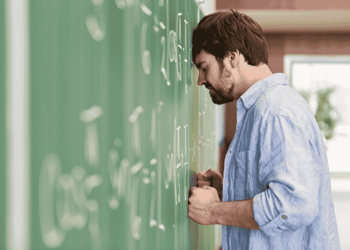 Man with his head against the wall with an angry expression and his fists clenched against the wall, in need of anger management inpatient treatment