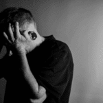 Black and white image with man holding his hands to his face in anger due to intermittent explosive disorder