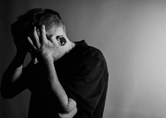 Black and white image with man holding his hands to his face in anger due to intermittent explosive disorder