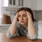 Woman sitting at the dining room table with her hands in her hair, crying, due to the opposite of depression, mani