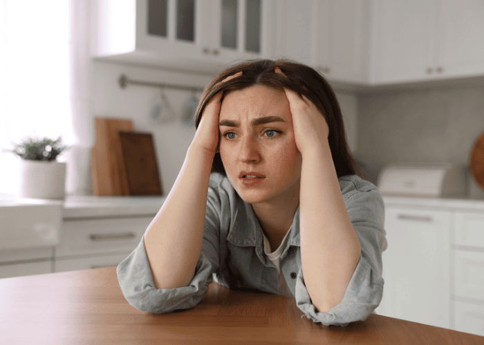 Woman sitting at the dining room table with her hands in her hair, crying, due to the opposite of depression, mani