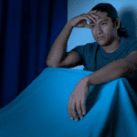 Man unable to sleep sitting up in bed at night, in need of sleep disorder treatment