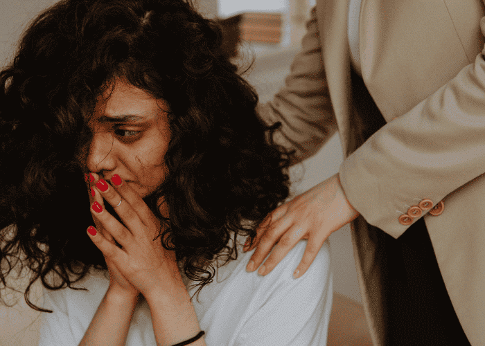 Woman facing forwards with her hands on her face, looking traumatized and in need of trauma treatment