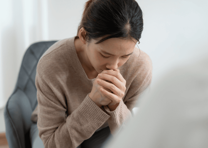 woman struggling with her mental health with her hands up to her face in an adjustment disorder treatment session