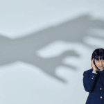 Woman in need of delusional disorder treatment with hands over her ears with a shadow representing delusions next to her