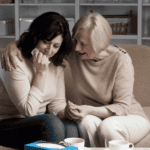 Two women, one woman crying in need of grief & loss support, and another woman comforting her