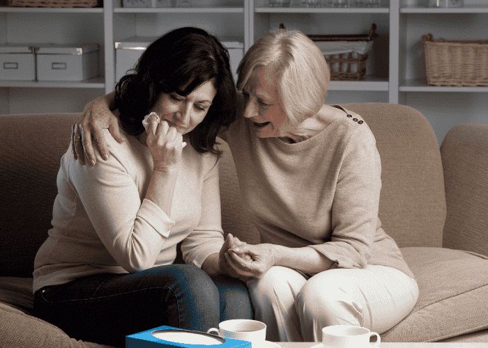Two women, one woman crying in need of grief & loss support, and another woman comforting her