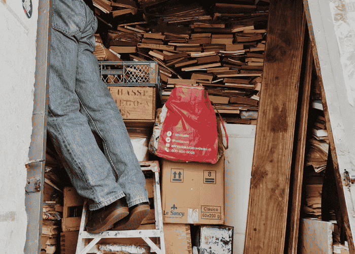 Man in need of hoarding disorder treatment on a ladder in front of a massive pile of books
