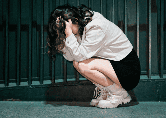 woman crouching and hiding her head in her hands due to mania in bipolar disorder