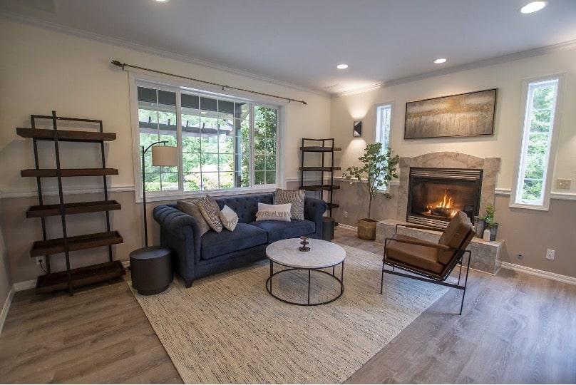 AMFM cozy living room with fireplace, navy sofa, and large windows providing natural light.