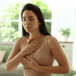 Woman with her hands on her chest taking deep breaths, wondering can deep breathing make anxiety worse?