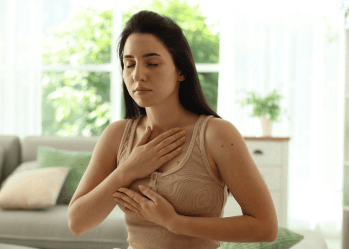 Woman with her hands on her chest taking deep breaths, thinking that deep breathing makes anxiety worse for her