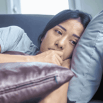 woman laying on the sofa with her hands to her face looking worried due to major depressive disorder in adults