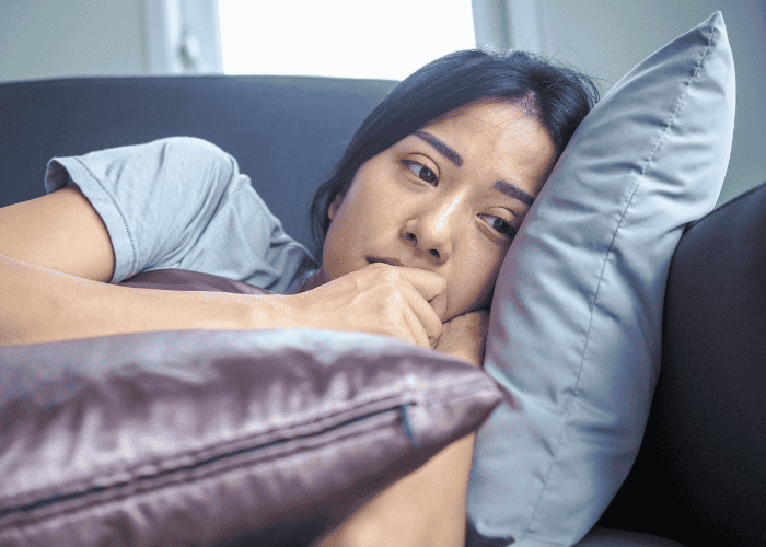 woman laying on the sofa with her hands to her face looking worried due to major depressive disorder in adults
