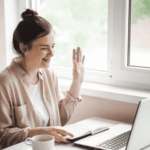 Woman sitting with her laptop open waving and smiling as she tries online therapy for bipolar disorder