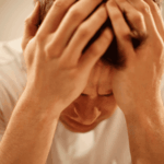 Man with head in hands looking distressed due to causes of bipolar disorder in adults