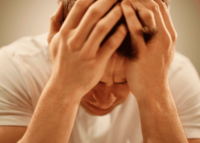 Man with head in hands looking distressed due to causes of bipolar disorder in adults