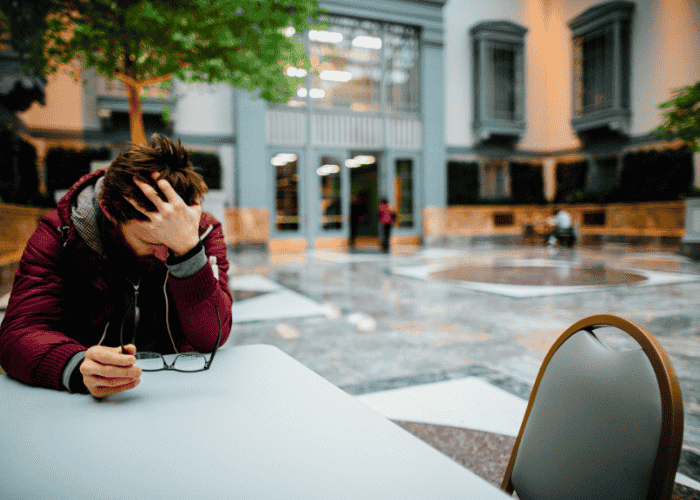 Man clutching his head in a public place, struggling with social anxiety disorder in adults