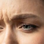 close-up of woman's blue eyes, her brow furrowed, holding in repressed or suppressed anger