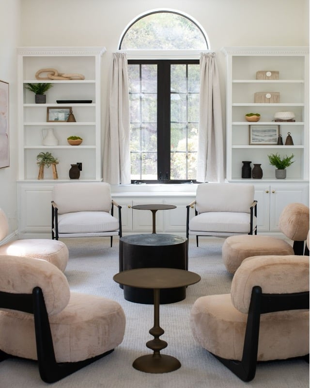 Modern minimalist living room with symmetrical white built-in shelving and cream furniture.