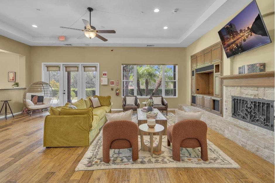 Spacious lounge with mustard yellow sofas, terracotta ottomans, stone fireplace, and large windows overlooking greenery.