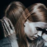 Red-haired woman with mood disorder crying and having a headache, experiencing bipolar depression and anxiety