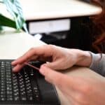 girl paying for purchase with a credit card, typing on a black keyboard, looking up bipolar treatment cost