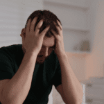 Man with his head in his hands due to california parity laws insurance denials