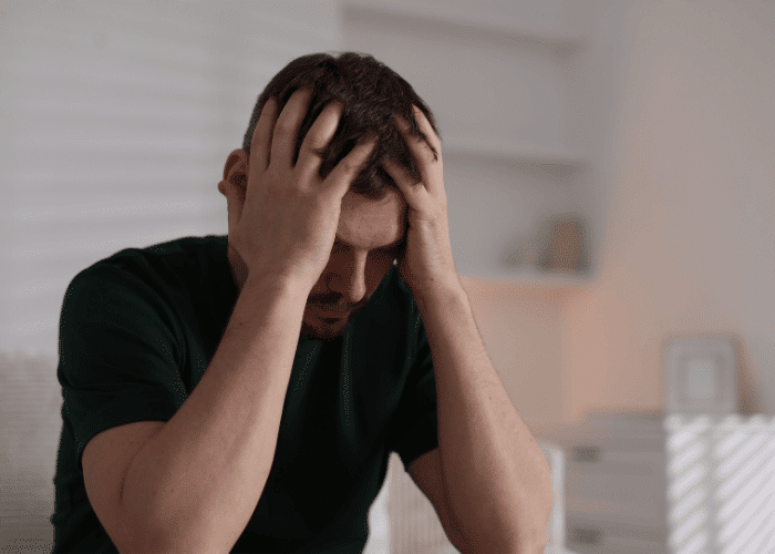 Man with his head in his hands due to california parity laws insurance denials