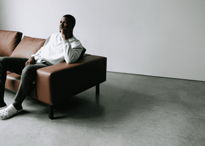 Man sitting on a couch on his own struggling with social isolation