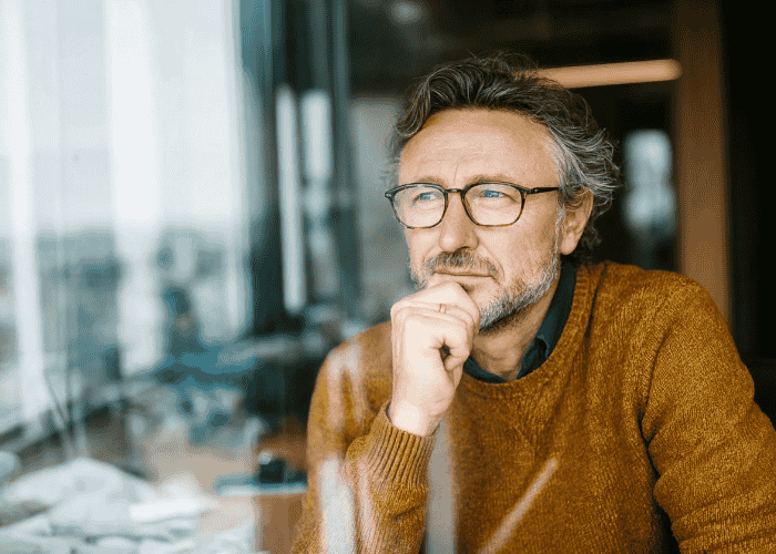 Man looking out the window into the distance in need of depersonalization and derealization disorder treatment